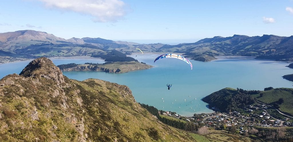 a photo of my friend paragliding above banks peninsula in the canterbury region new zealand